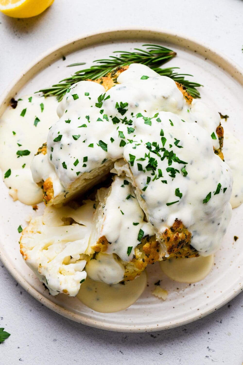 whole roasted cauliflower on a plate with cheese sauce