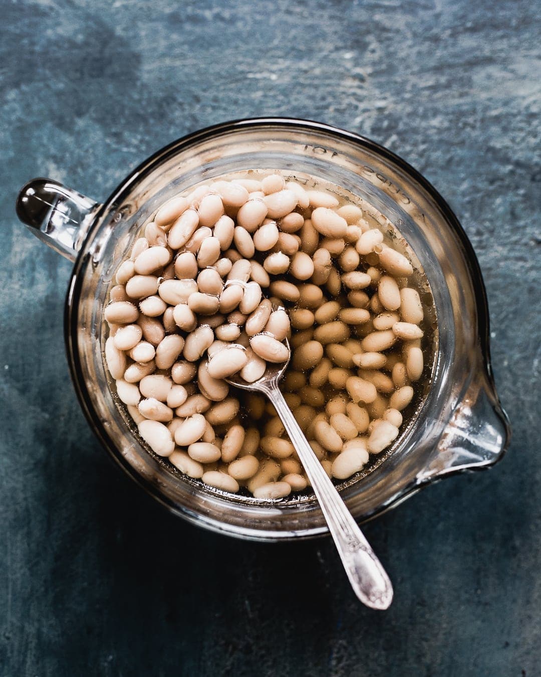 cooking great northern beans in a glass bowl with spoon