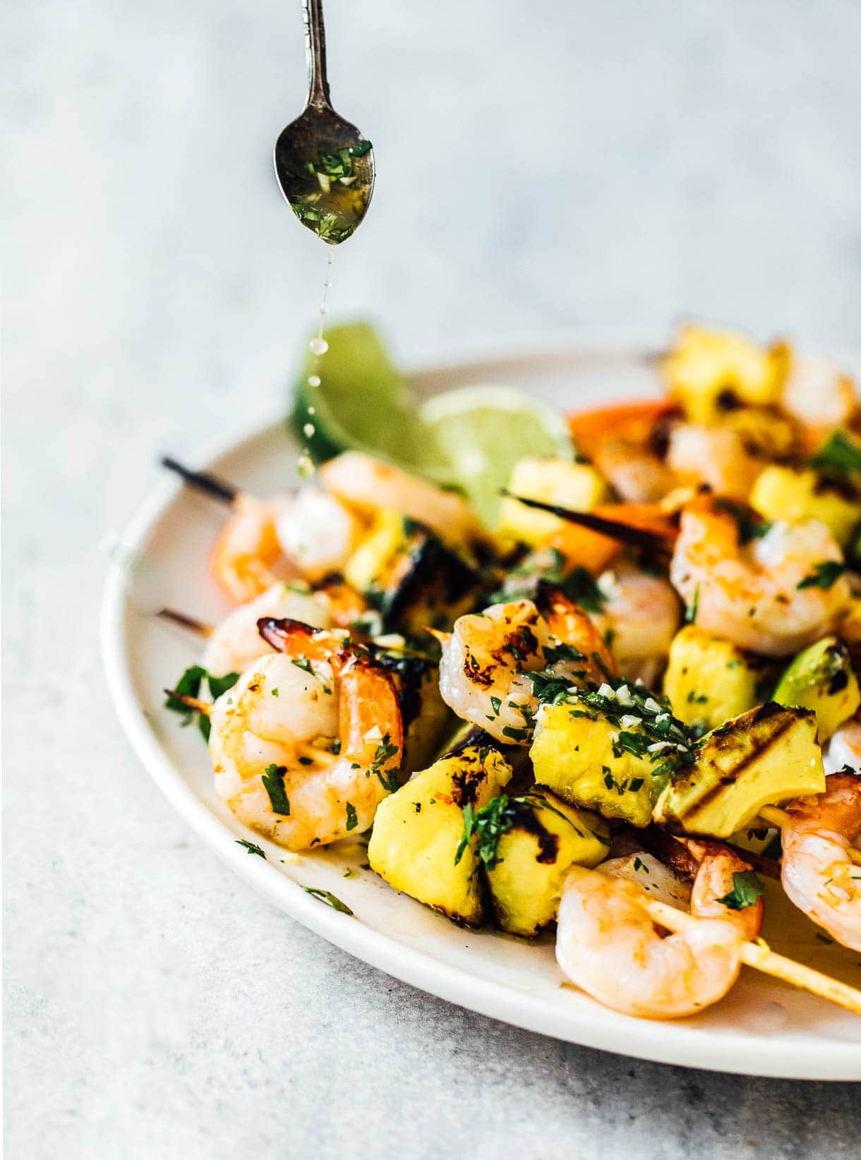 drizzling sauce over grilled shrimp and avocado skewers