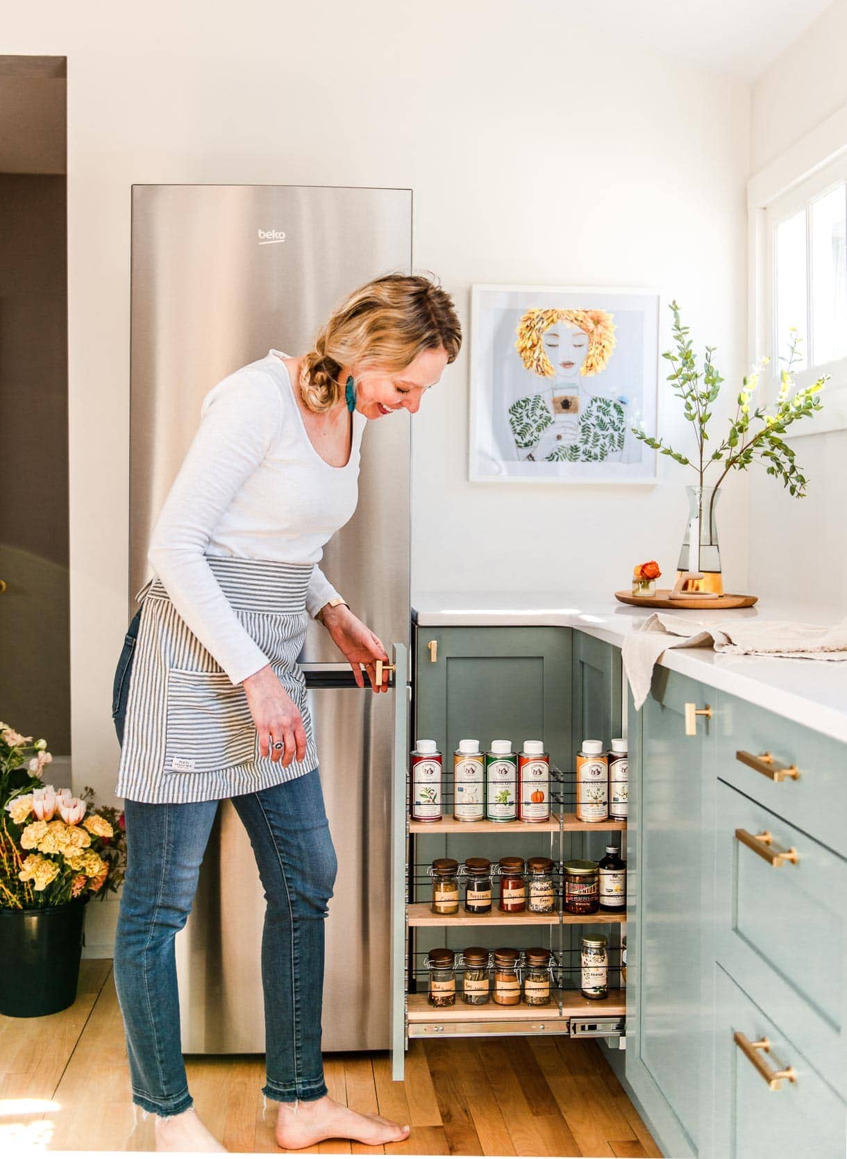 woman pulling out vertical spice cabinet, green kitchen cabinets