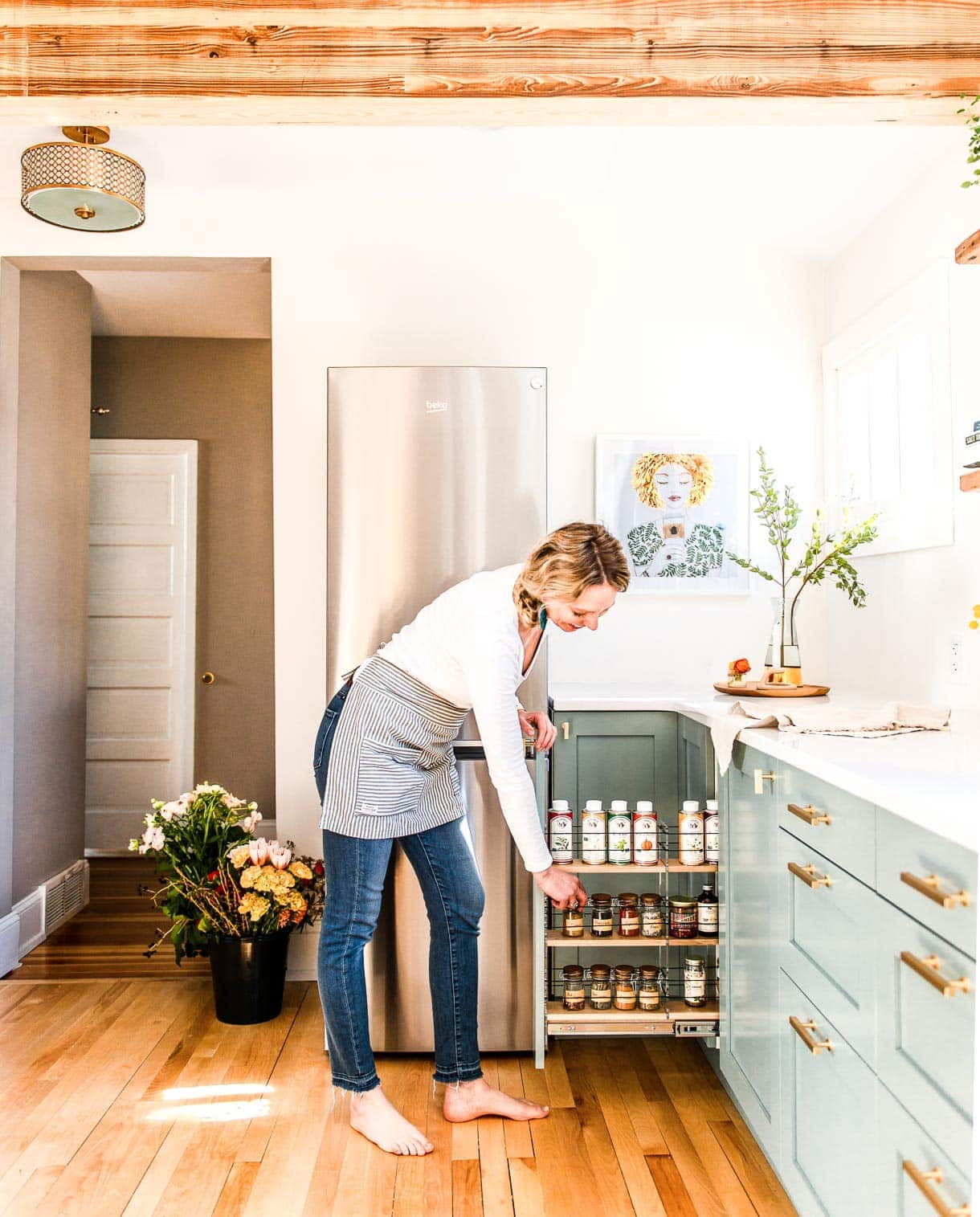 White Kitchen with mounted drum lighting and beko refrigerator, vertical spice rack