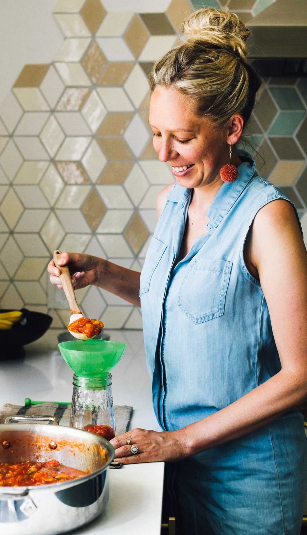 woman ladling salsa into a ball canning jar, preserving salsa