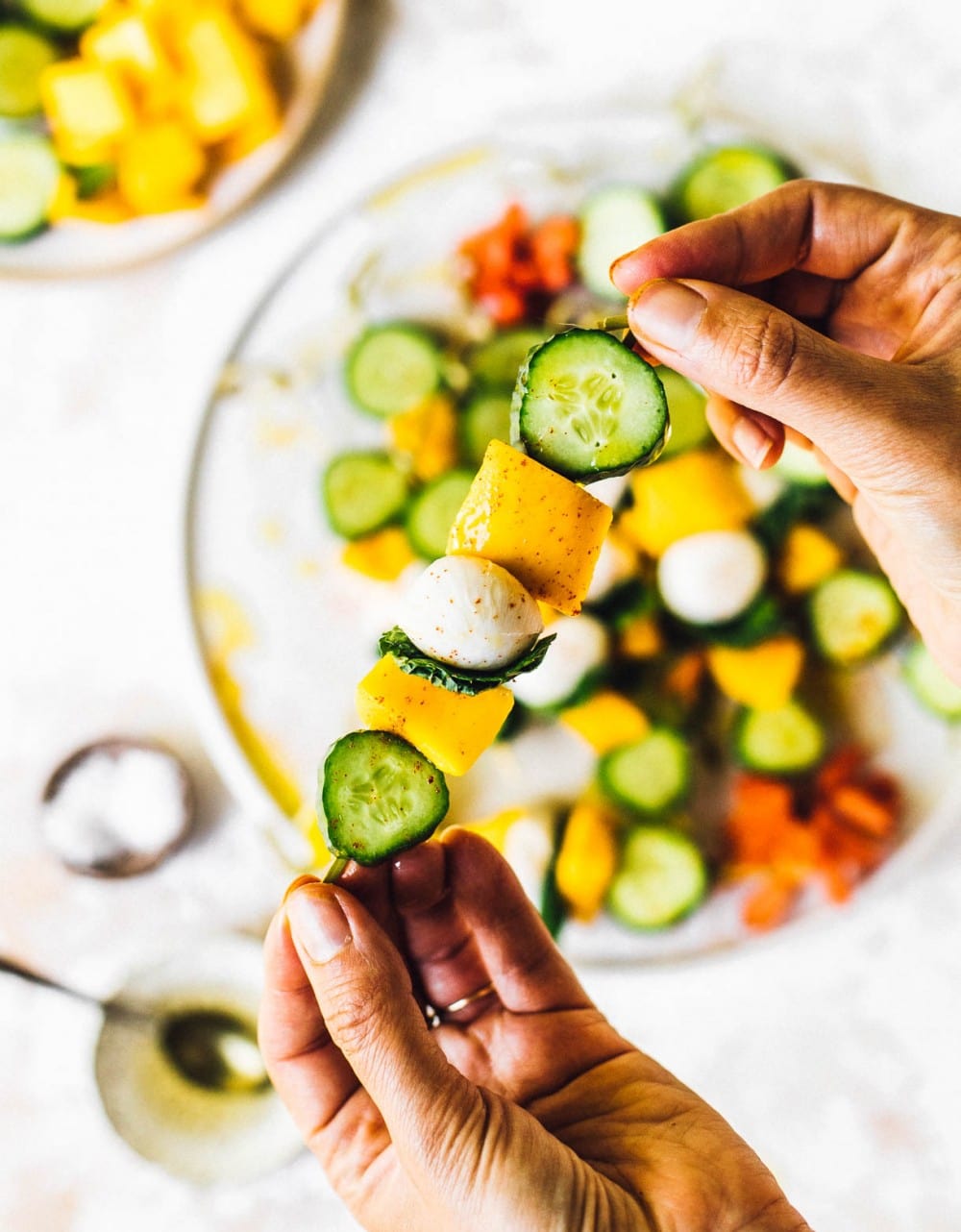 holding cucumber mango fruit kabobs in hand