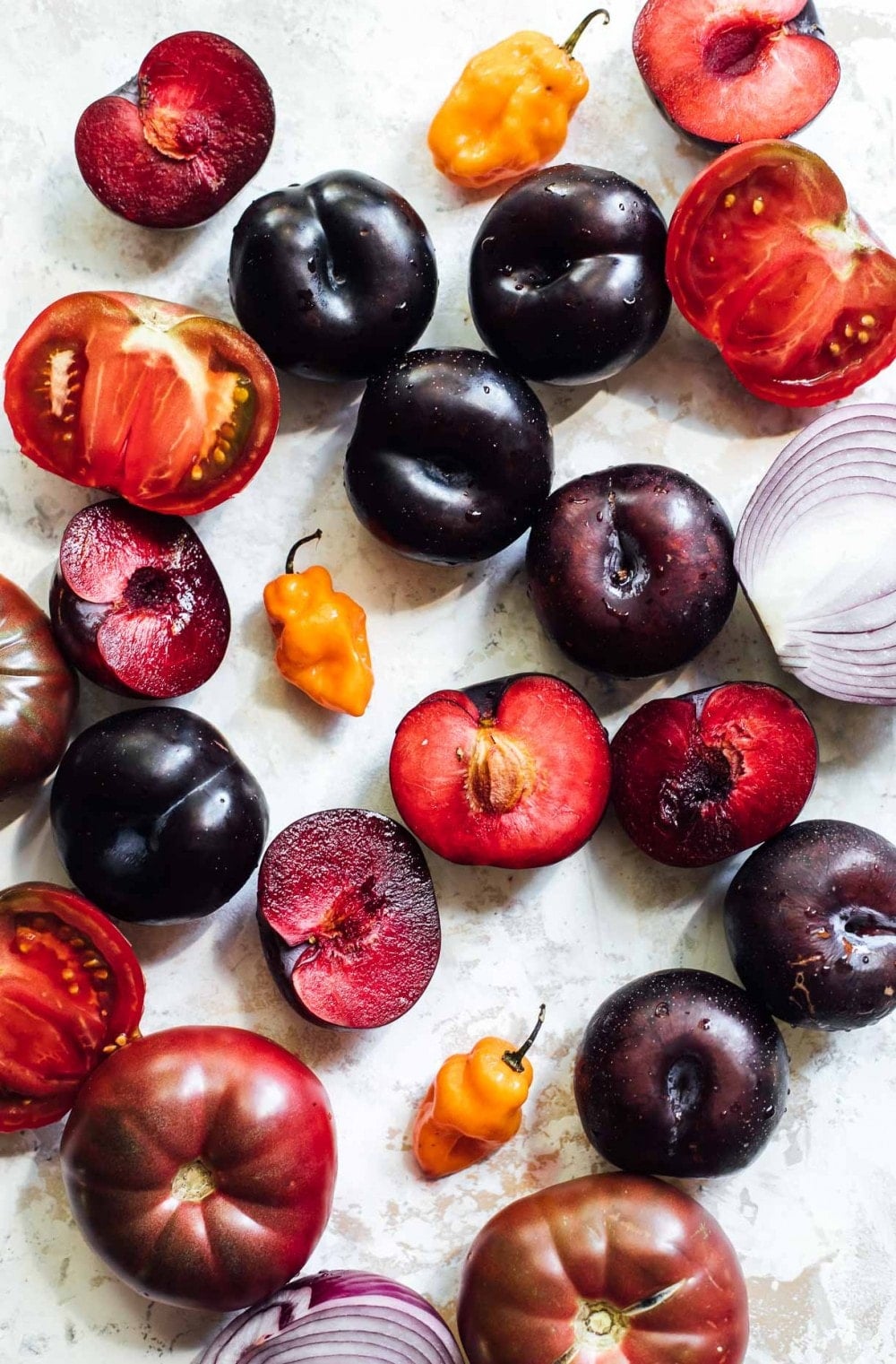 plums, tomatoes, and habanero peppers laying on a surface
