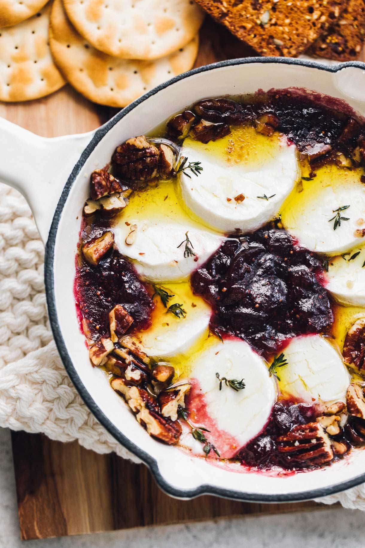 baked goat cheese in cast iron skillet surrounded by crackers