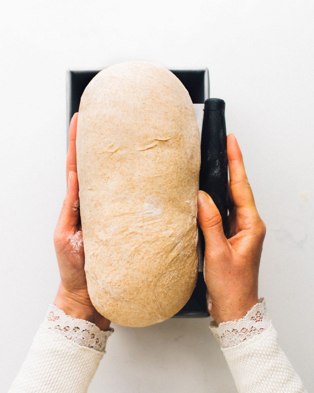 putting unbaked sourdough sandwich bread dough into pan