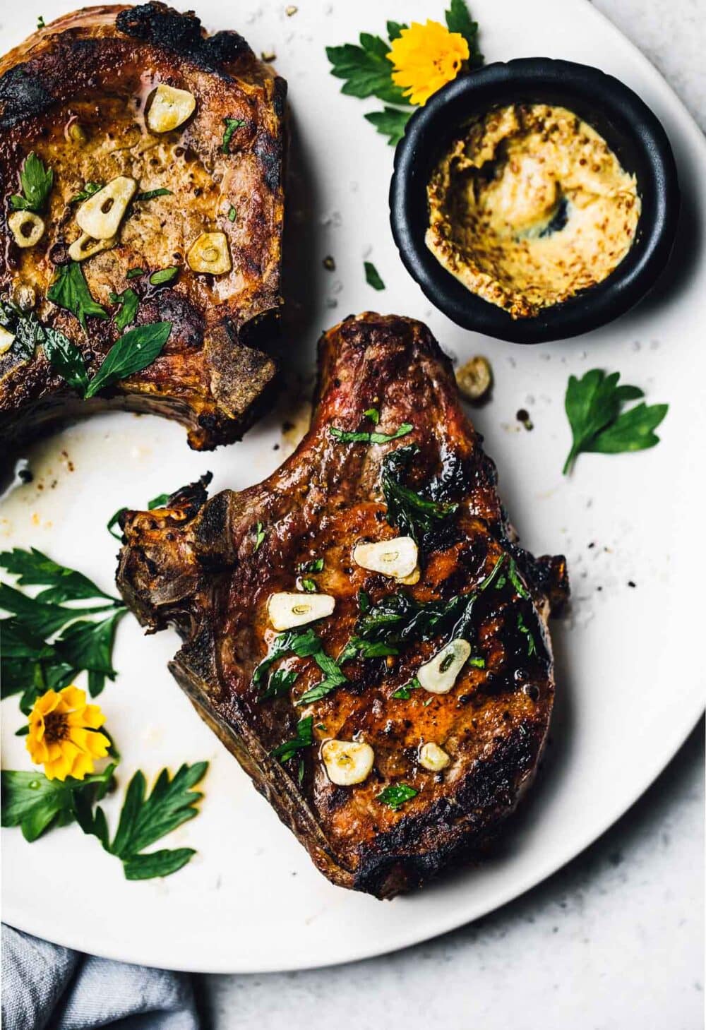 grilled bone in pork chops with garlic butter on a white plate