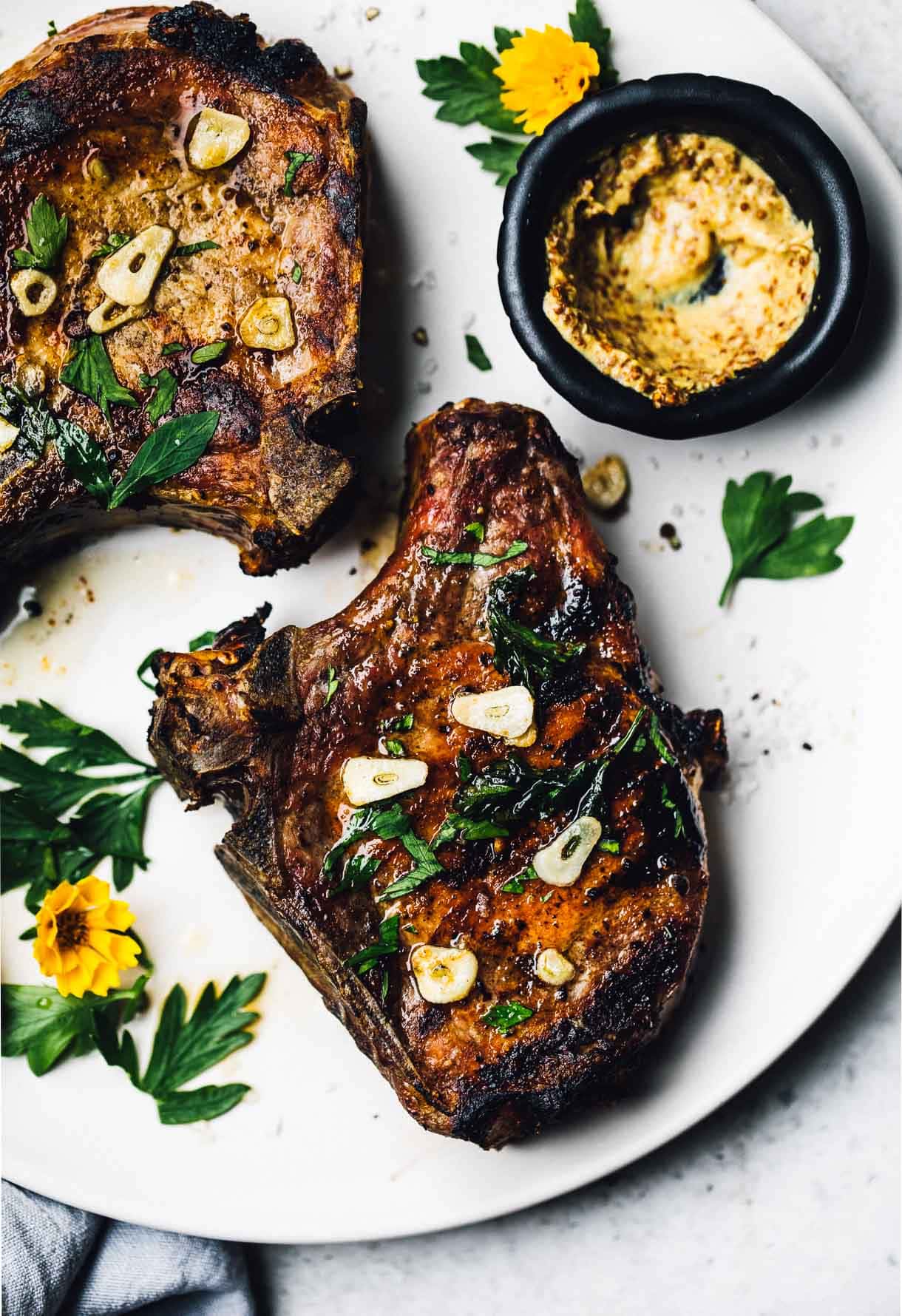 grilled bone in pork chops with garlic butter on a white plate