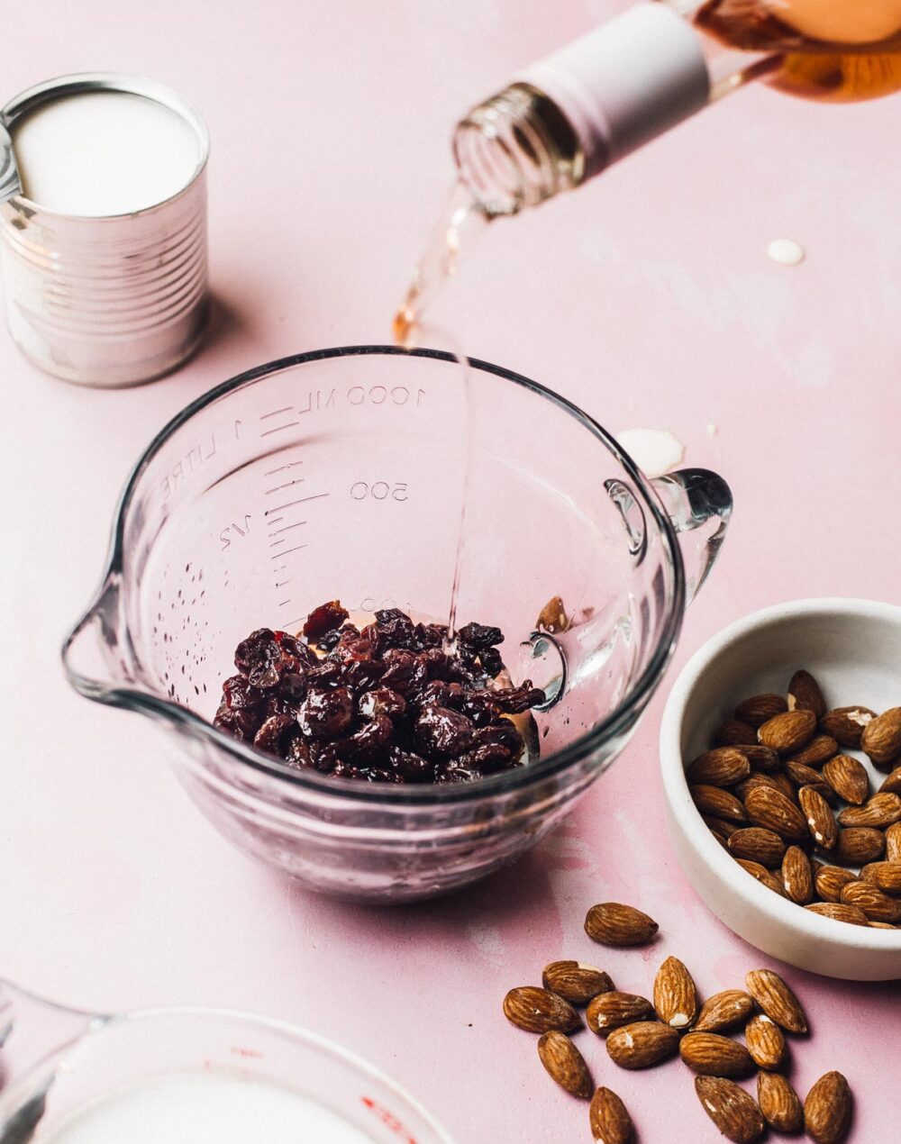 pouring rose wine over dried tart cherries, in a glass measuring cup