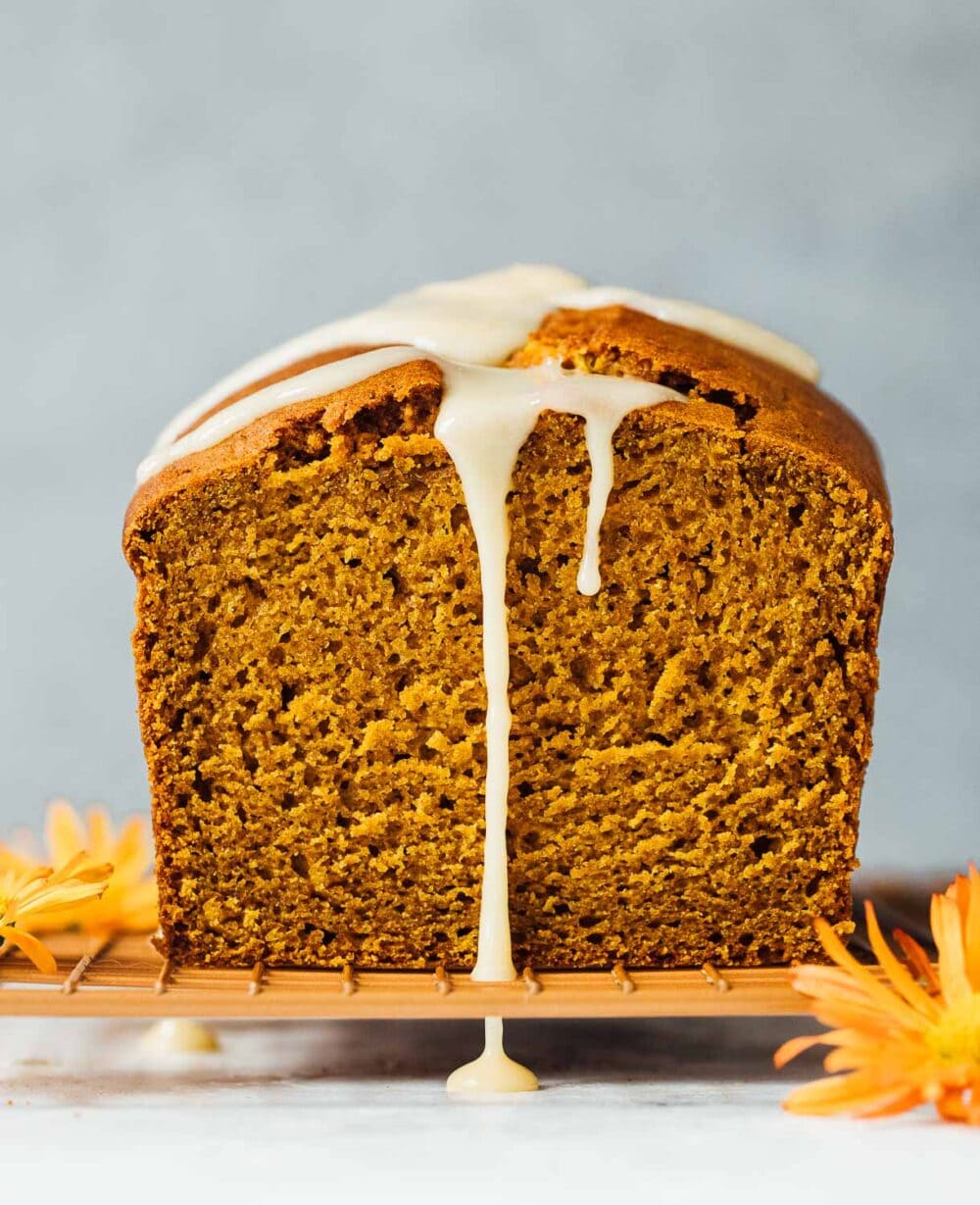 sourdough discard pumpkin bread with glaze dripping down