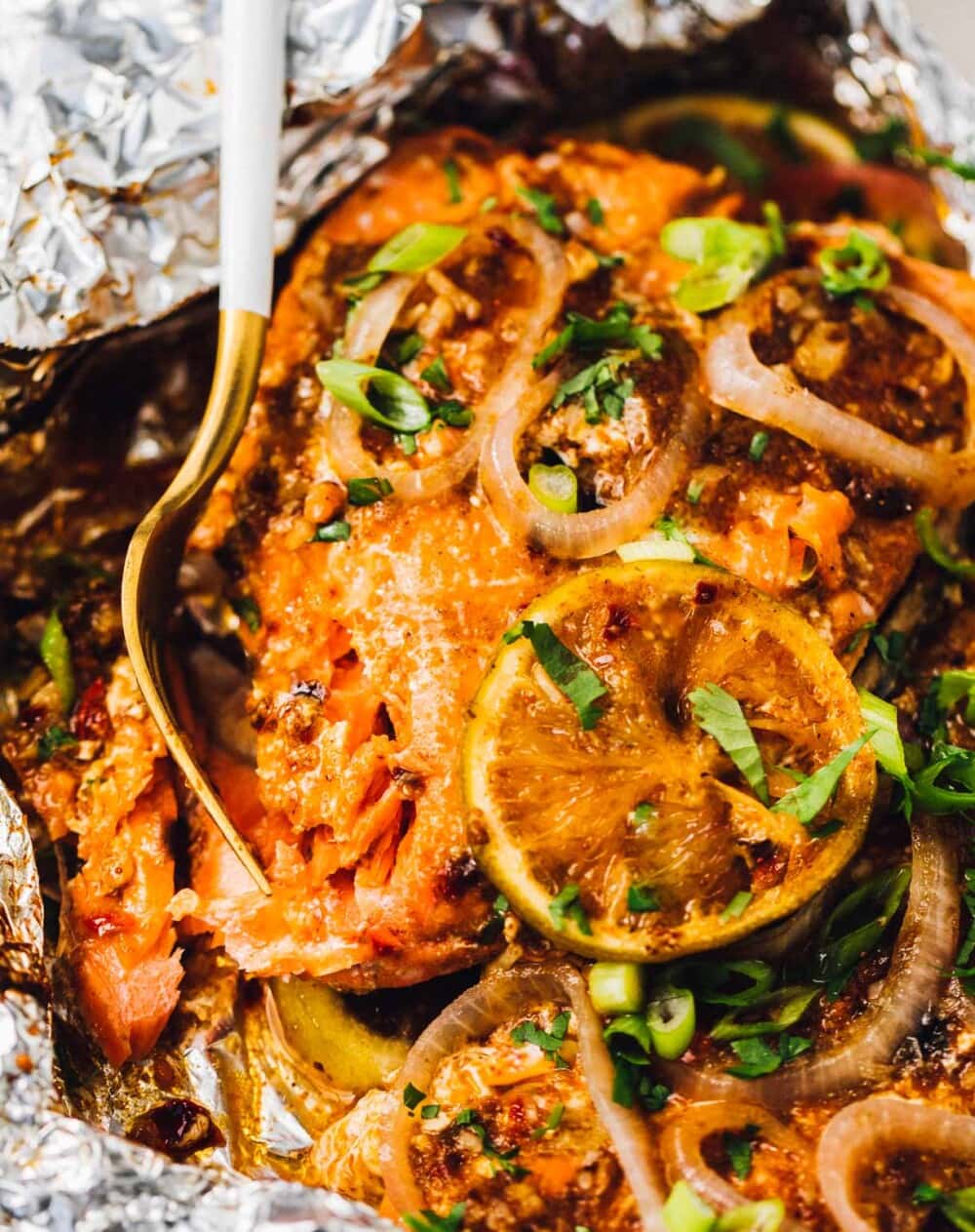 grilled salmon in foil, fork flaking some of the fish off.
