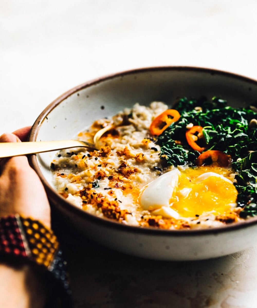eating savory oatmeal with a gold spoon in a ceramic bowl