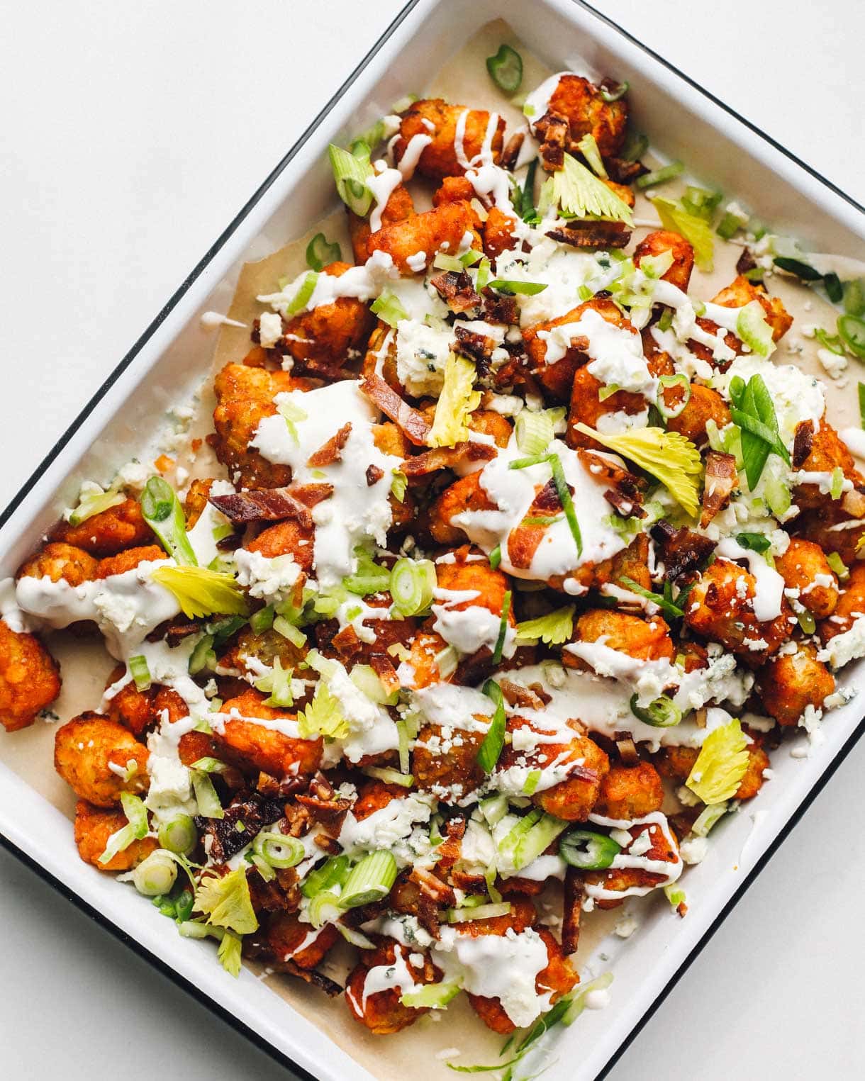 loaded buffalo tater tots in a white enamel pan.