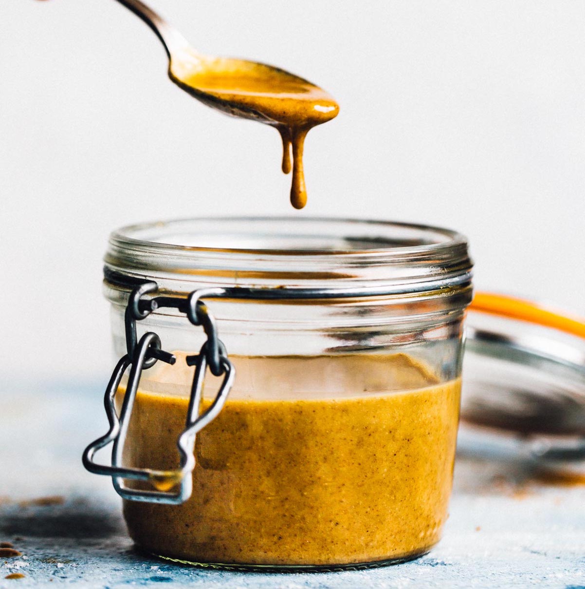 walnut butter in a jar, with spoon dripping the butter