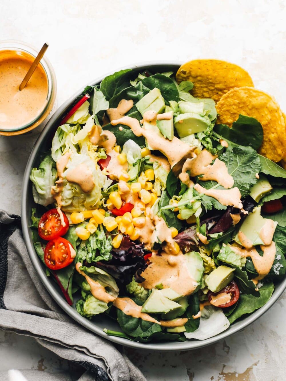 southwest salad in a blue bowl with salad dressing to the right of it