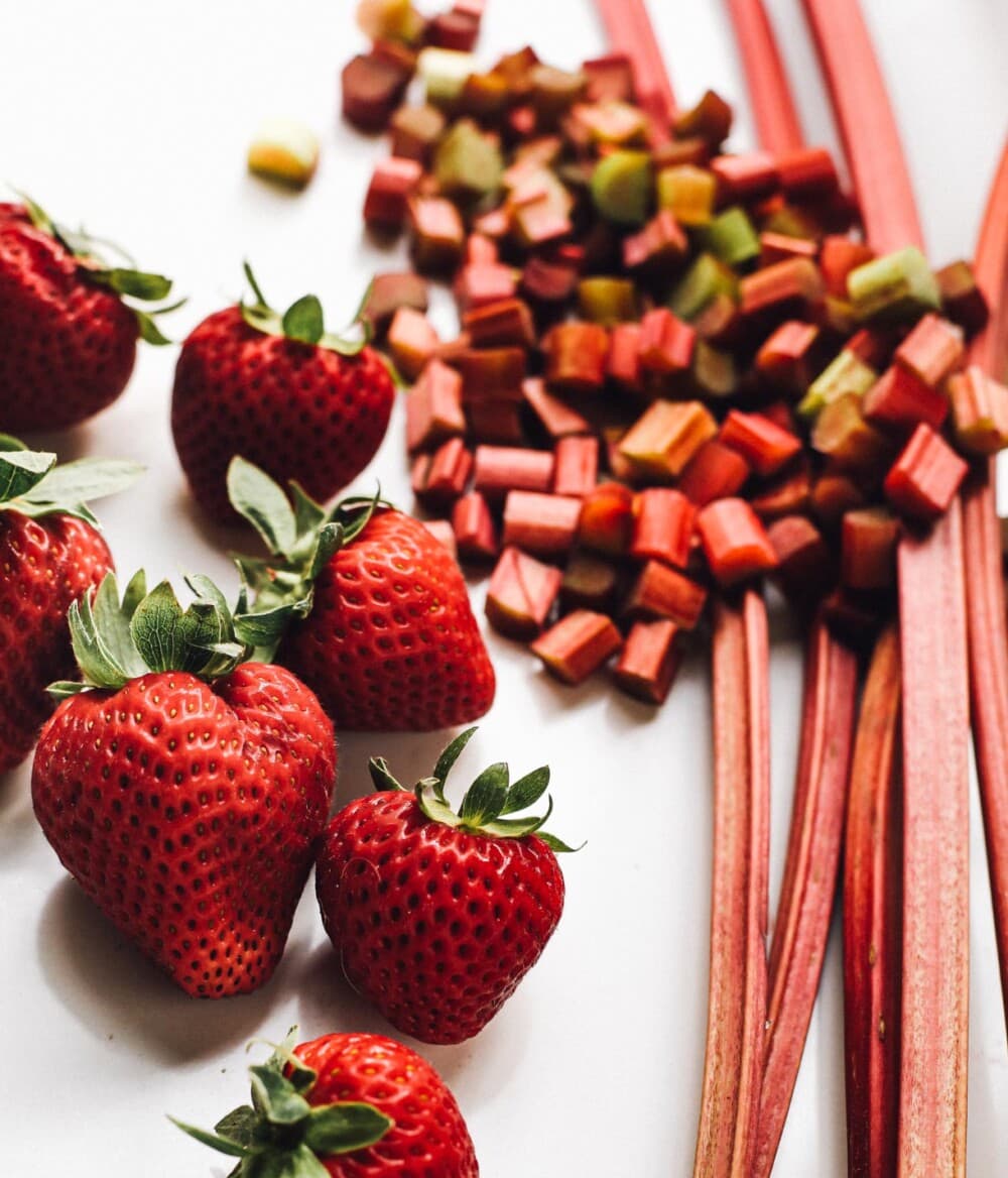 fresh strawberries and rhubarb on white surface