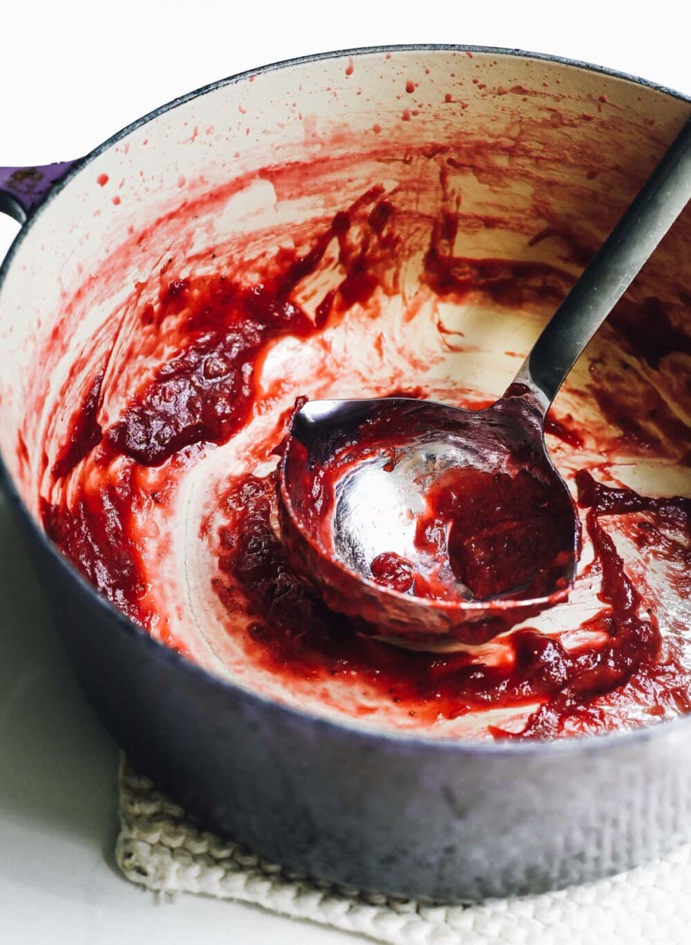 dutch oven where strawberry jam has been made, with ladle.