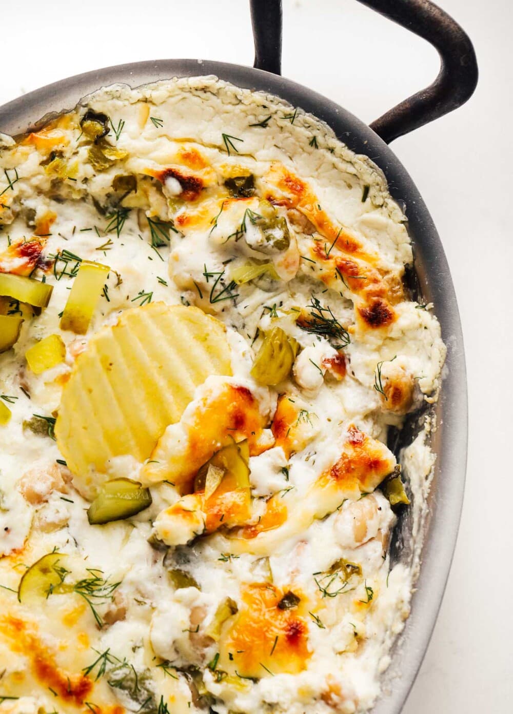 baked dill pickle dip with potato chip for scooping
