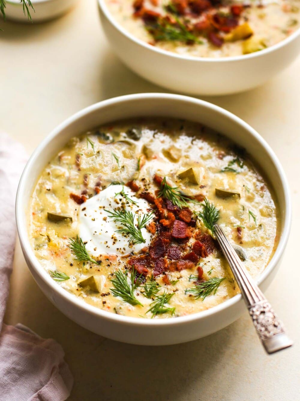dill pickle soup in white bowl with spoon