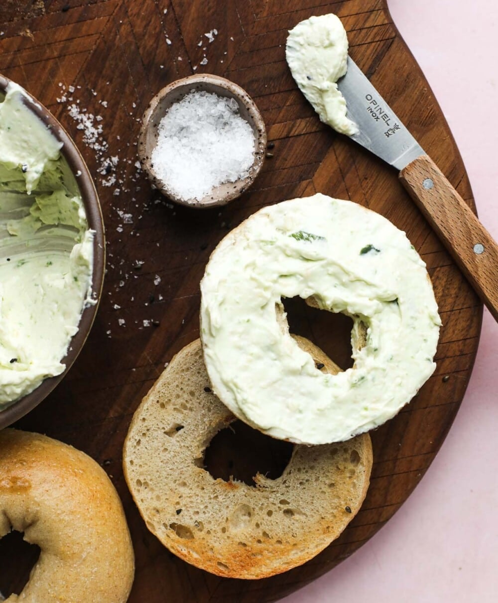 jalapeno cream cheese on bagel with flaky salt next to it.