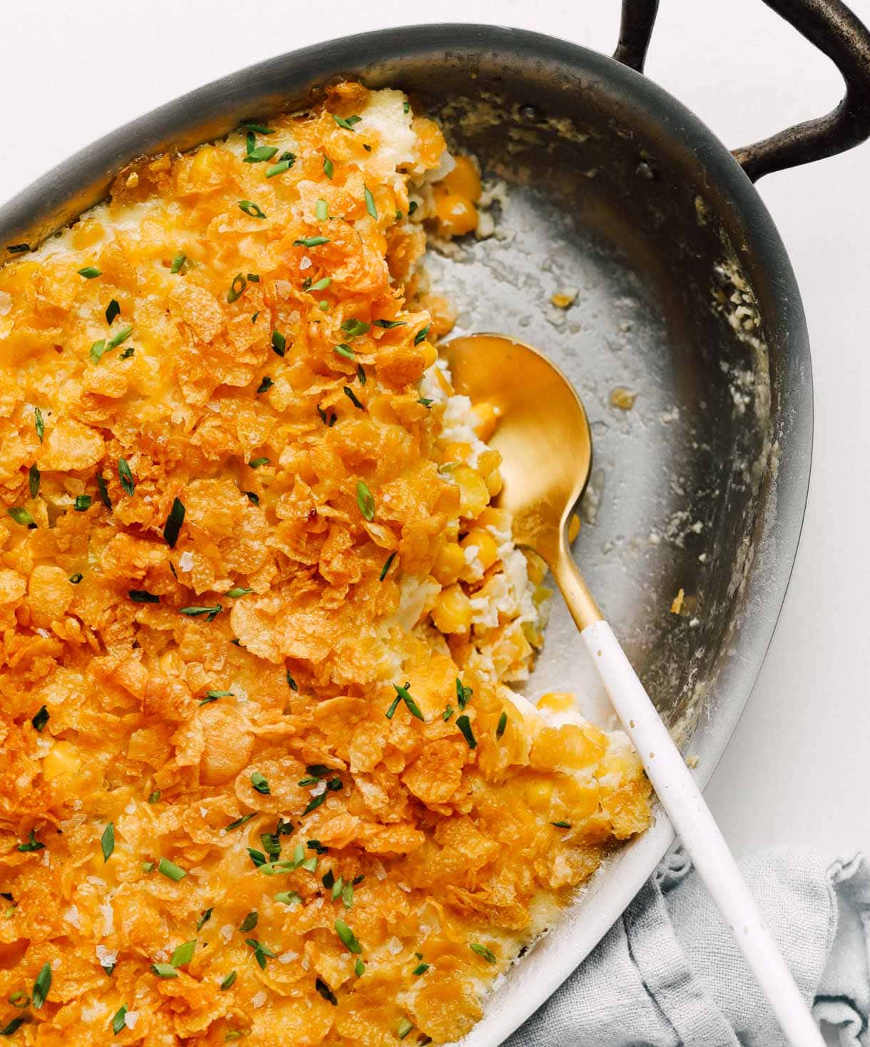 baked corn in a baking dish with gold spoon