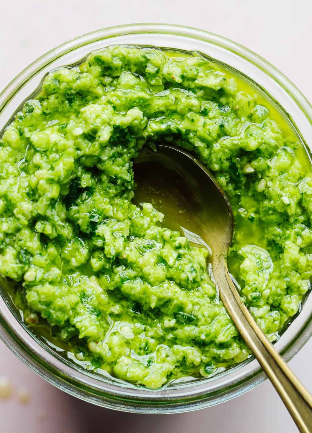 garlic scape pesto in a jar with gold spoon