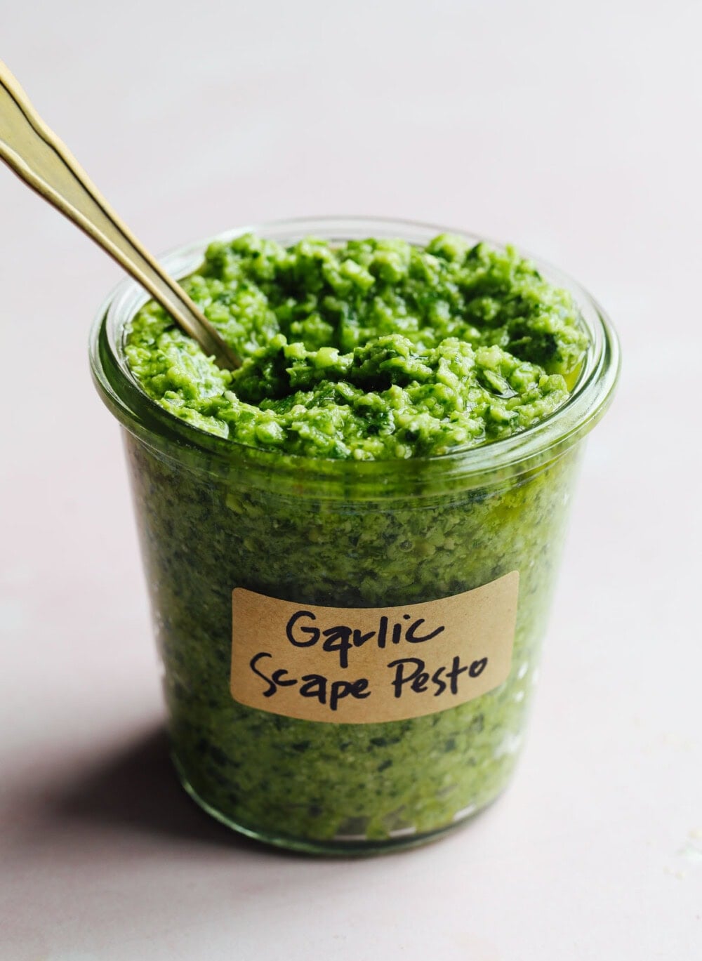 garlic scape pesto in a glass jar with label on it.