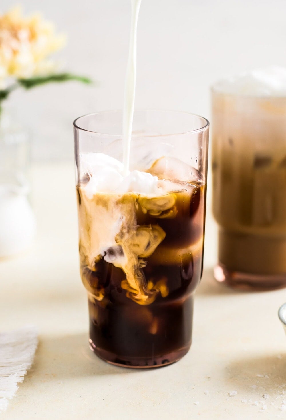 Pouring milk into a glass with espresso